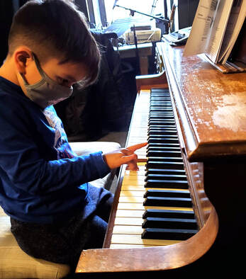 Picture of a young kid playing piano at his piano lesson. Our piano instructors will help you or your kid learn piano with ease.