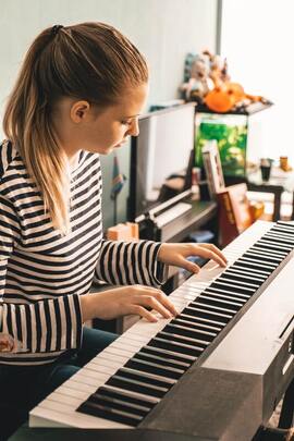 We have the best piano lessons. This is a picture of an adult woman playing piano. Piano is fun, makes you smarter, and our piano classes will really help you develop your skills quickly./