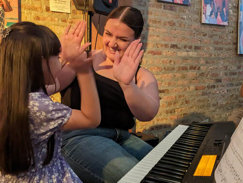 Photo of our instructor Madelyn giving her student a high five after an awesome musical performance on piano at our recital in 2023